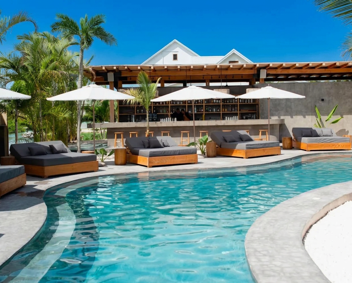Pool club with loungers, umbrellas and a full bar under clear blue sky