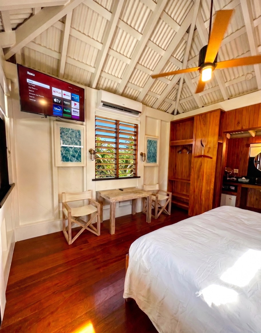 Cottage interior with vaulted wood ceiling, ceiling fan, wall-mounted smart TV, desk and hardwood floors